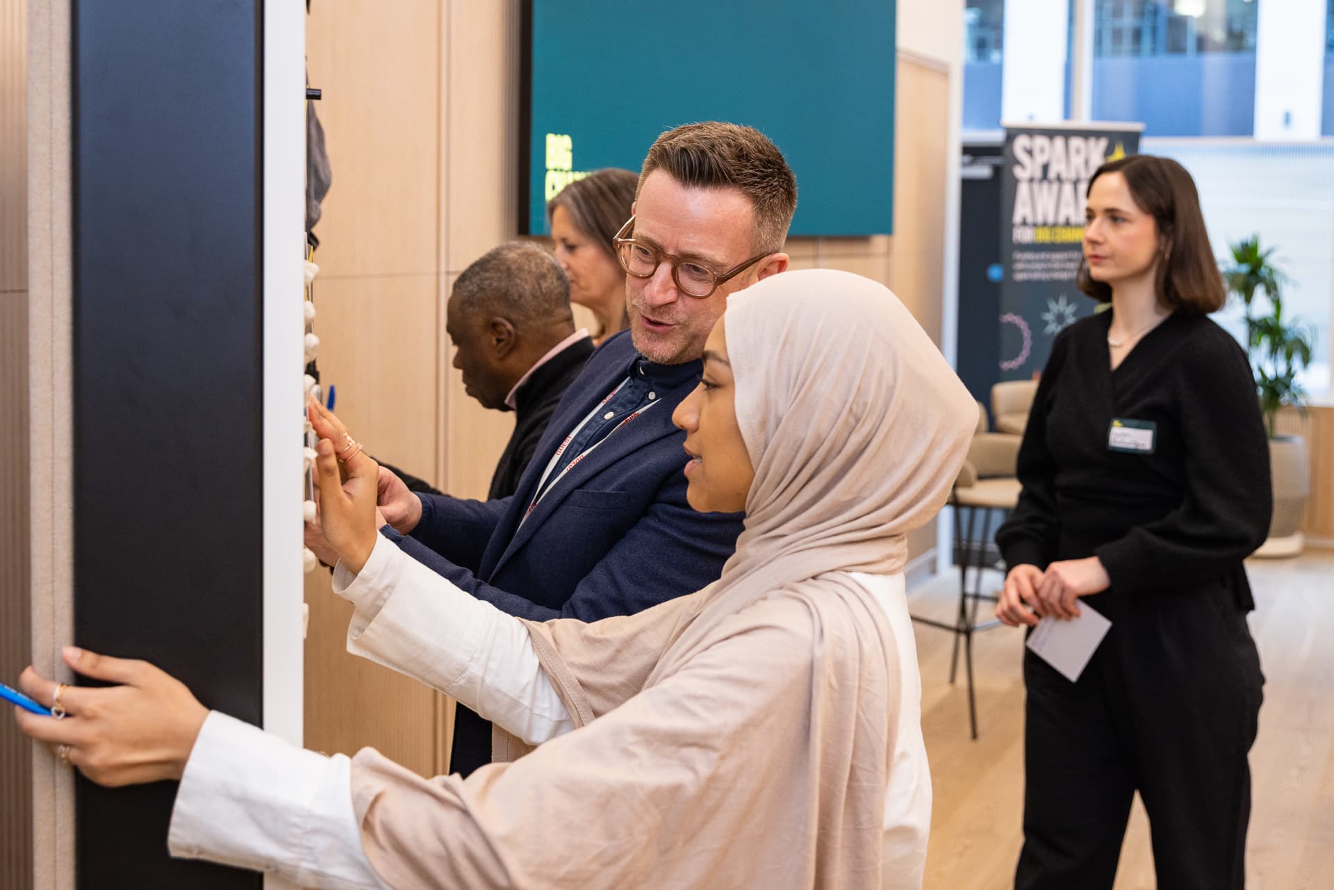 Two people looking at a noteboard at the Sparks Award Event